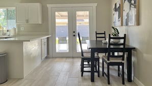A kitchen with white cabinets, a dining table with chairs, and a door leading to a balcony. - Downtown Gilbert *Pet-Friendly* Getaway (Gilbert)