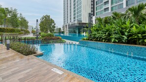 A modern residential building with a swimming pool surrounded by lush greenery. - Greenfield Residence at Bandar Sunway (Petaling Jaya)
