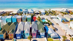 A coastal residential area with colorful houses, a beach, and a swimming pool. - Salty Air, Ocean Views, Private Heated Pool - Steps to the Sand (Panama City Beach)