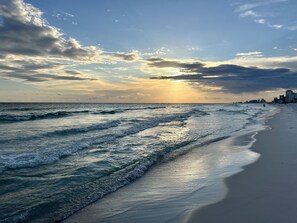 A beach with waves, a city skyline in the background, and a sunset. - Steps to Beach • Private Heated Pool • 4 King Beds (Panama City Beach)