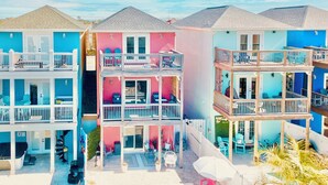 A multi-story hotel with balconies, a swimming pool, and outdoor seating areas. - Salty Air, Ocean Views, Private Heated Pool - Steps to the Sand (Panama City Beach)