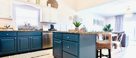 Una cocina moderna con armarios azul oscuro, una encimera de granito y una isla central.