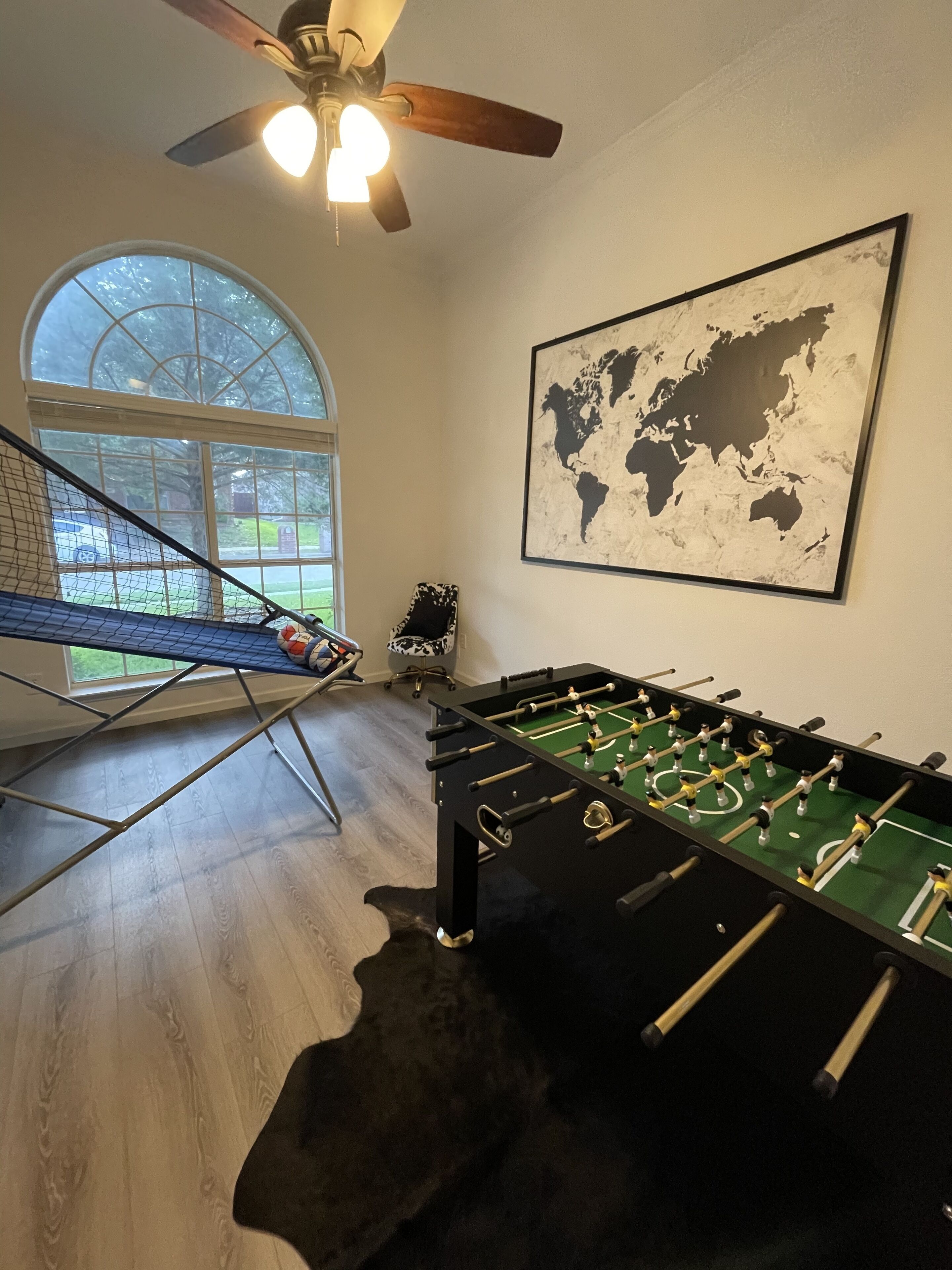 A room with a foosball table, a large window, and a world map on the wall.