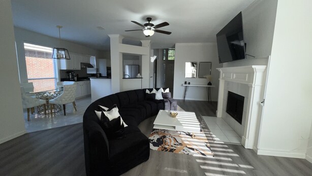 A modern living room with a black sectional sofa, a white coffee table, and a fireplace.