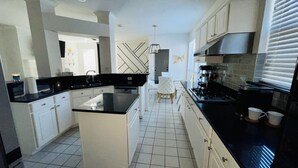 A modern kitchen with white cabinets, black countertops, and a central island.
