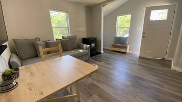 A spacious living room with a wooden dining table, a sofa, and a fireplace.