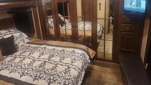 A hotel room with a large bed, a television, and a sliding door leading to a bathroom. - Camper on campsite (Jamestown)