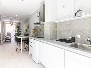 A modern kitchen with a white countertop, stainless steel sink, and a dining area with a table and chairs.