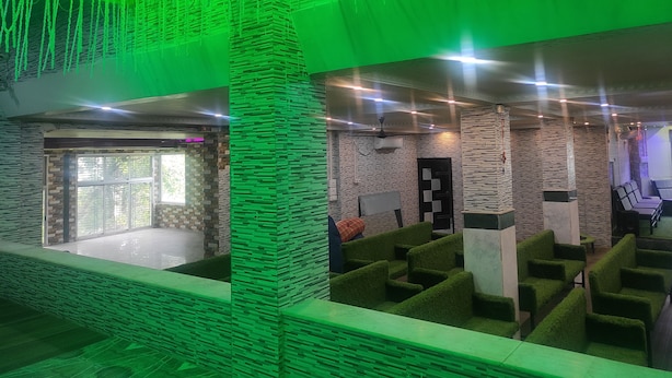 Un hall d’entrée avec un éclairage vert, des murs en pierre et des espaces aménagés avec des sièges.