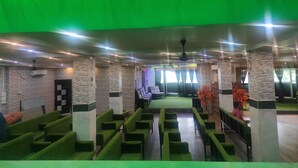 Un hall d’entrée spacieux, doté de coins salons recouverts de moquette verte, d’une scène et d’un design moderne agrémenté d’éléments en pierre et en bois.
