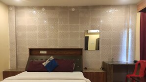 Une chambre d’hôtel avec un lit, un bureau, une chaise et un miroir au mur.