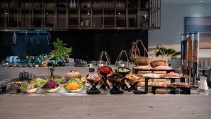 A buffet setup with various food items and a large window in the background.