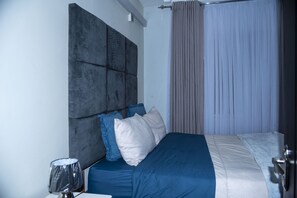 Une chambre à coucher moderne avec un grand lit, une tête de lit et un rideau.