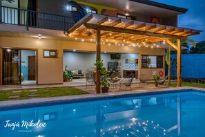 A modern house with a pool, outdoor seating, and a covered patio area.