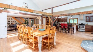 A spacious kitchen with wooden beams, a dining area with a large wooden table and chairs, and a staircase leading to another level.