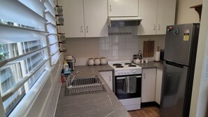 Een moderne keuken met witte kasten, een roestvrijstalen koelkast, een inbouwoven en een fornuis.