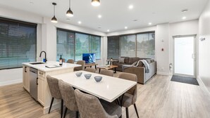 A modern kitchen with a central island, dining area with chairs, and a sofa in a living area. - 3-bedroom house Daily/Monthly Rates Available (Parksville)