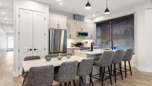 A modern kitchen with white cabinets, stainless steel appliances, and a central island with bar stools. - 3-bedroom house Daily/Monthly Rates Available (Parksville)