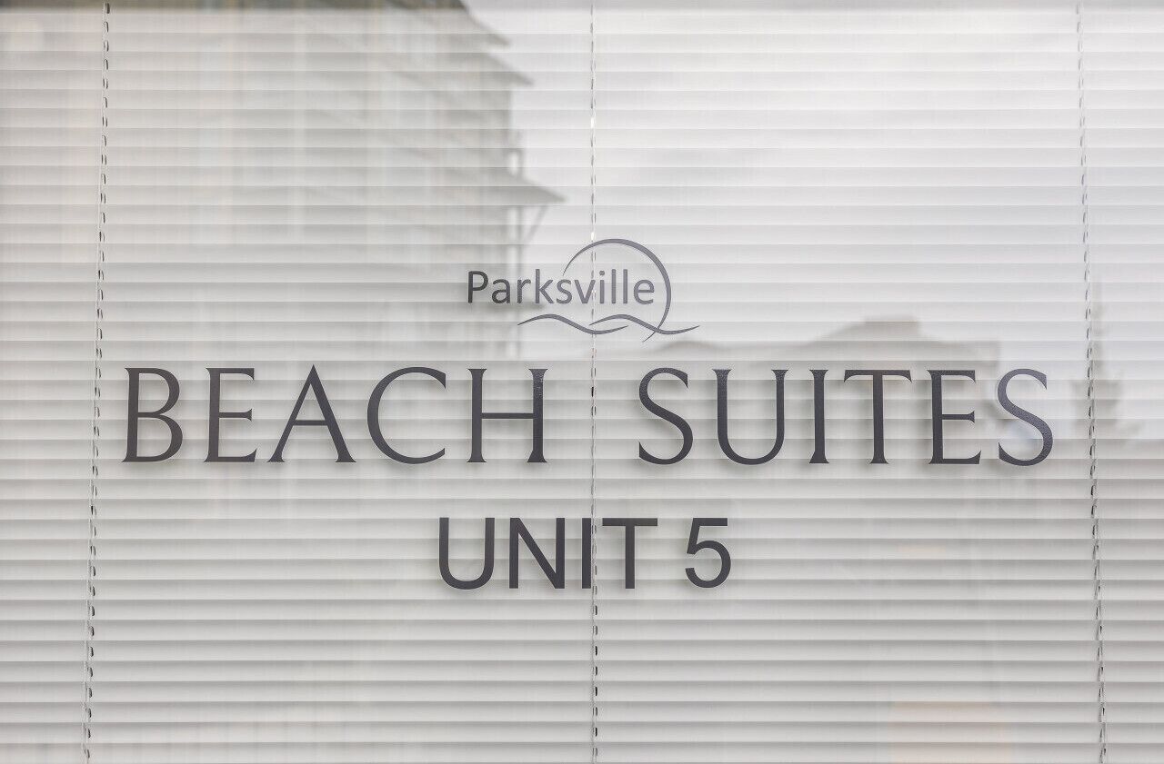 A sign for 'BEACH SUITES UNIT 5' with a logo above it.