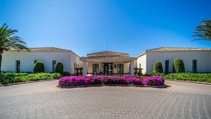 Un bâtiment à deux étages doté d’une entrée centrale, entouré d’une allée pavée et agrémenté de fleurs violettes.