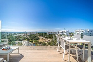 Eine Terrasse mit Tisch und Stühlen mit Blick auf ein Wohngebiet und das Meer.