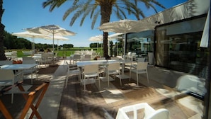 Un espace extérieur aménagé en terrasse, avec des tables et des chaises, des parasols et une vue sur le paysage.