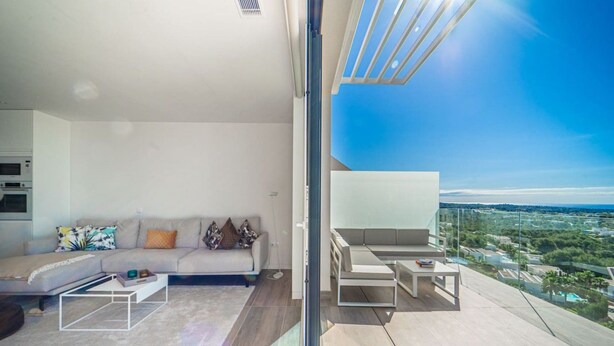 Un salon moderne avec un canapé, une table basse et un balcon offrant une vue sur la ville.