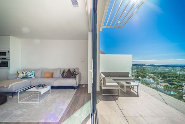Een moderne woonkamer met een bank, salontafel en een balkon met uitzicht op de stad.