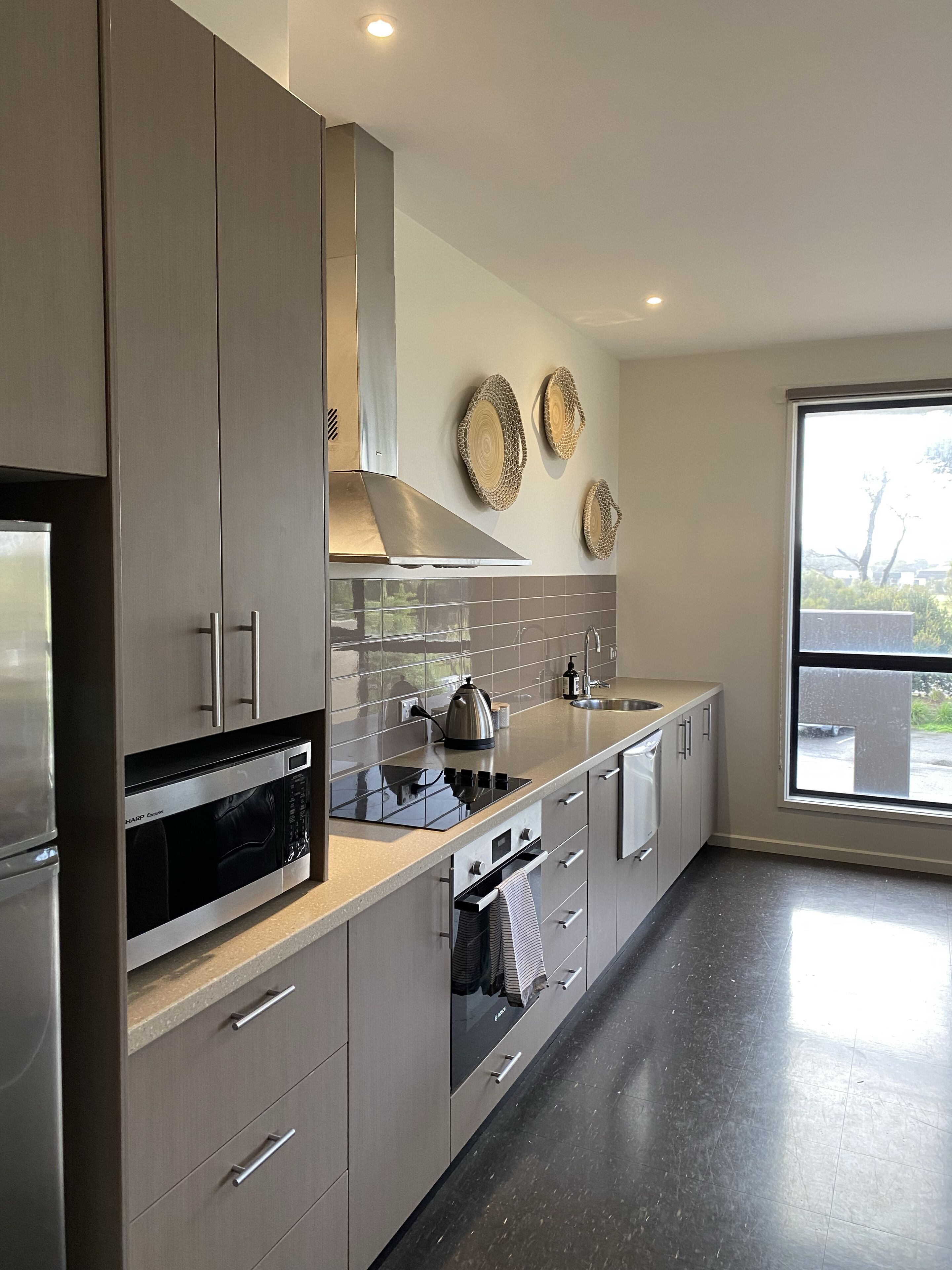A modern kitchen with stainless steel appliances, a large window, and a view of the outdoors.