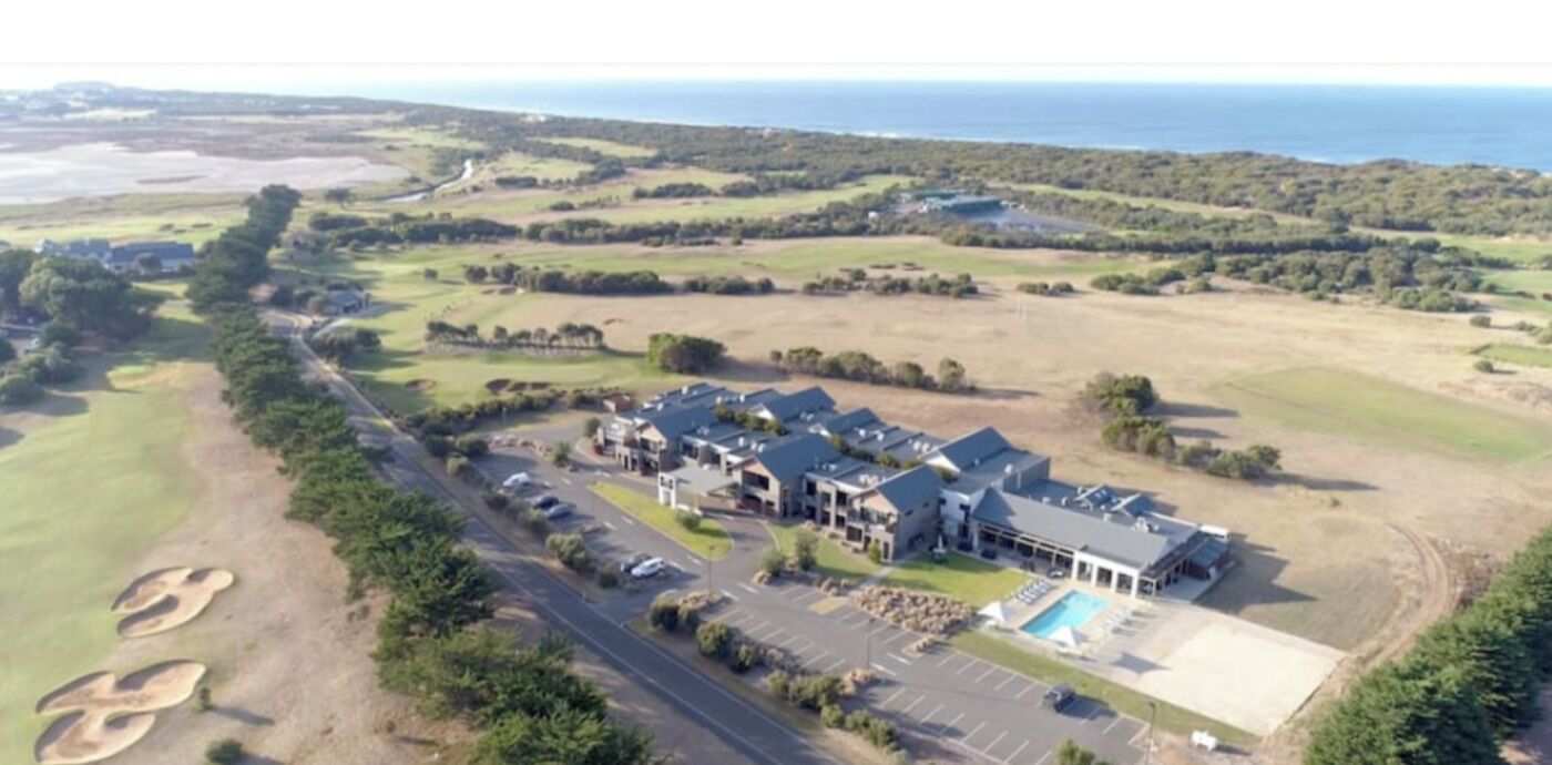 An aerial view of a golf course with a clubhouse and swimming pool.