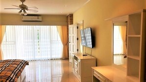 A hotel room with a bed, a desk, a television, and a ceiling fan. - 1-bed in View Talay 5D - Sleeps 2 - Close to Beach (Pattaya)