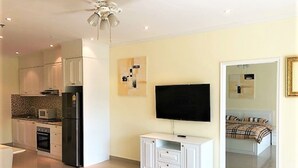 A modern kitchen with a built-in oven, microwave, and refrigerator. There is a flat-screen TV mounted on the wall and a white cabinet below it. - 1-bed in View Talay 5D - Sleeps 2 - Close to Beach (Pattaya)
