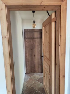 Une porte en bois dotée d’une simple poignée, qui donne sur une pièce dont le sol est recouvert de carreaux.