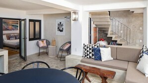 Un salon moderne avec un canapé, des fauteuils, une table basse et un escalier.