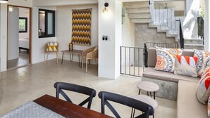 Un salon moderne avec un canapé, une table à manger et un escalier.