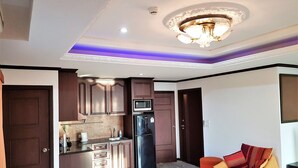A compact kitchen with dark wooden cabinets, a black refrigerator, and a built-in microwave. - Pratumnak 1 bed Condo With sea View (Pattaya)