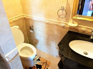 Et badeværelse med toilet, vask og spejl.