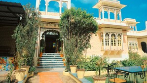 A traditional building with ornate architecture, a staircase leading to the entrance, and potted plants around the area. - Ranakpur Hill Resort (Desuri)