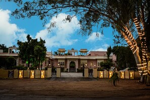 A large, multi-story building with a central entrance, surrounded by trees and illuminated by string lights. - Ranakpur Hill Resort (Desuri)