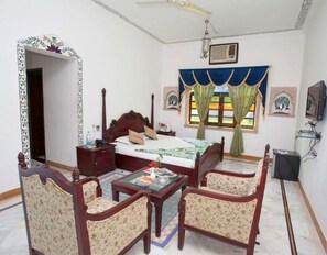 Relax in a traditional room with a large bed, bedside table, and comfortable armchairs.