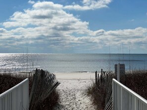 A beach path leading to the shore with a signboard.