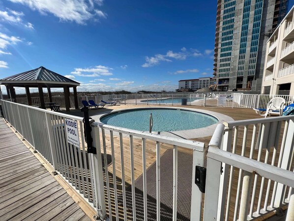 A pool area with a 'KIDDIE POOL' sign, a wooden deck, and a gazebo.