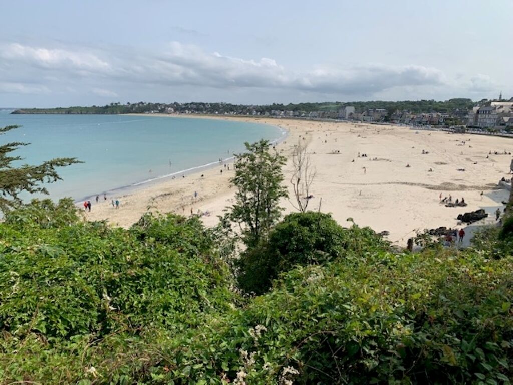 A beach with people and buildings in the background.