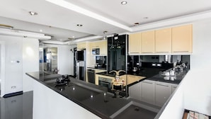 A modern kitchen with black countertops, stainless steel appliances, and light-colored cabinets. - 20th Floor 2-bed Condo With Stunning Views (Pattaya)