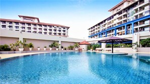 A hotel with a swimming pool, multiple balconies, and potted plants. - 20th Floor 2-bed Condo With Stunning Views (Pattaya)