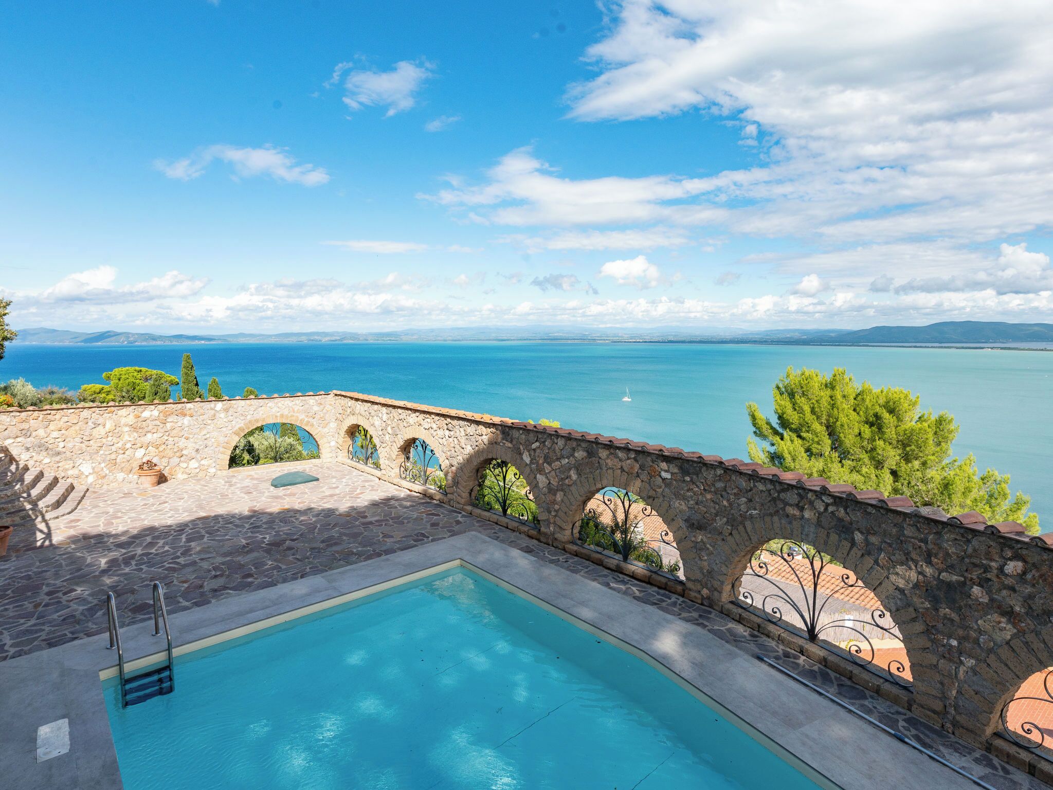 Une piscine en pierre offrant une vue sur la mer et les montagnes lointaines.