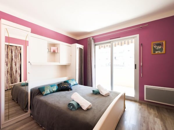 Une chambre à coucher avec un lit, une armoire, une fenêtre avec des rideaux et un tableau accroché au mur.