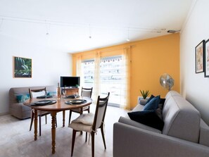 A modern living room with a dining table, sofa, and TV.