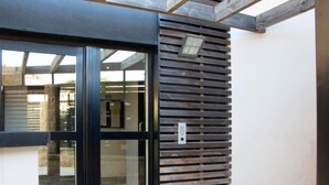 A modern building entrance with a glass door and a wooden slatted wall. - Stella Marine by Interhome (Carnac)