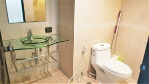 Ein Badezimmer mit einem Waschbecken aus Glas, einer Toilette und einer Duschkabine.